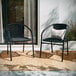 Two Flash Furniture black rattan arm chairs on an outdoor patio.