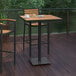 A Flash Furniture natural faux teak table with a black metal base on an outdoor patio.