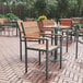 Flash Furniture Finch natural faux teak slat arm chair on a brick patio with a table and chairs.