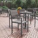 A Flash Furniture Finch gray faux teak slat table and chairs on a brick patio.