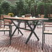 A Flash Furniture rectangular faux teak table with a gray metal X-frame on a brick patio.