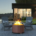 A Flash Furniture bronze steel portable fire pit with a fire in it on an outdoor patio.