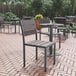 A Flash Furniture Finch Gray Faux Teak slat side chair and table on an outdoor patio.