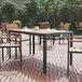 A Flash Furniture rectangular natural faux teak table and gray metal frame on a brick patio.