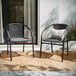 Two Flash Furniture Lila Gray Rattan stackable arm chairs on a rug outside.