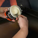 A person using a spoon to spread Blackstone seasoning on a griddle.