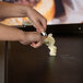 A person's hands using a spoon to spread butter on a grill.