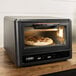 A Blackstone electric air fryer and pizza oven with a pizza inside.