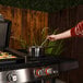 A woman using a Blackstone outdoor griddle to cook food on a patio.