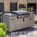 A Blackstone outdoor griddle on a counter in an outdoor kitchen with white cabinets and black handles.