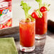 Two glasses of Ruby Kist Tomato Juice garnished with celery on a table.