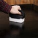 A hand using a black and white sponge to clean a table.