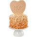 A heart-shaped cake with the word "Mom" on top in a white bowl.