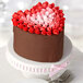 A heart-shaped cake with pink and red frosting on a white plate.