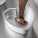 Liquid chocolate being poured into a Wilton heart-shaped cake pan.