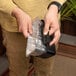 A person holding a small foil bag with Blackstone Rear Grease Cup Liners inside.