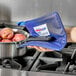 A person using a Tucker Safety blue poly-cotton hot pad to hold a pot of apples.