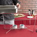 A man using a Vollrath wire chafer stand to hold two metal containers on a counter.