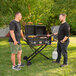 Two men using a Blackstone Tailgater grill on a table outdoors.
