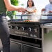 A woman cooking food on a Blackstone 5-Person Chef's Table outdoor griddle.