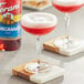 A glass of red pomegranate syrup on a table with a drink in it.