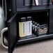 The interior of a Blackstone outdoor griddle with cabinets and a shelf with bottles and lighters.