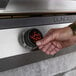 A hand turning the temperature on a Blackstone electric drop-in griddle.