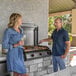 A man and woman standing next to a Blackstone electric drop-in griddle on an outdoor patio.