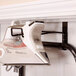 A Household Essentials ironing board mounted on a wall with a hook holding a steam iron.