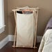 A white cloth laundry bag in a Household Essentials wooden laundry hamper.