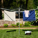 A Household Essentials dual height outdoor umbrella drying rack with clothes drying on it.