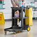 A man holding a Lavex Premium black and yellow janitor cart kit.
