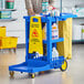 A man pushing a Lavex Premium blue janitor cart with cleaning supplies.