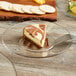 A slice of cheesecake with a brown and white swirl on top sits on an Anchor Hocking glass plate next to a fork.