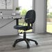 A Boss black leather mid-back office chair with wheels and adjustable arms in a room.