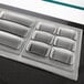 A stainless steel silver tray with six metal compartments on a counter.
