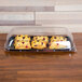 A Sabert Mozaik black plastic catering tray with pastries on it.