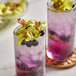 A glass of purple drink with a Green Orchid flower on top.