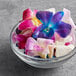 A bowl of mixed color orchids on a table in a salad bar.