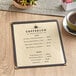 A menu on a table in a coffee shop with a cup of coffee.