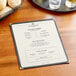A Choice natural linen menu on a table with bread and a glass of wine.