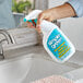 A person spraying Simple Green Lime Scale Remover into a sink.