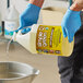 A person in blue gloves pouring Simple Green Concentrated Carpet Cleaner from a white jug.