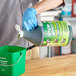 A person wearing blue gloves pouring Simple Green into a bucket.