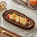 A rectangular brown Acopa china tray with food on a table.