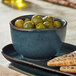 A table set with a Skyfall Blue China bouillon cup filled with green olives and crackers.