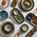 A table with Acopa Highlands Skyfall Blue bouillon cups, plates, and utensils.