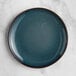 An Acopa Highlands skyfall blue coupe china plate on a marble surface.