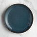 An Acopa Highlands skyfall blue coupe china plate on a marble surface.