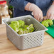 A person cutting broccoli in a Vollrath stainless steel steam table pan.